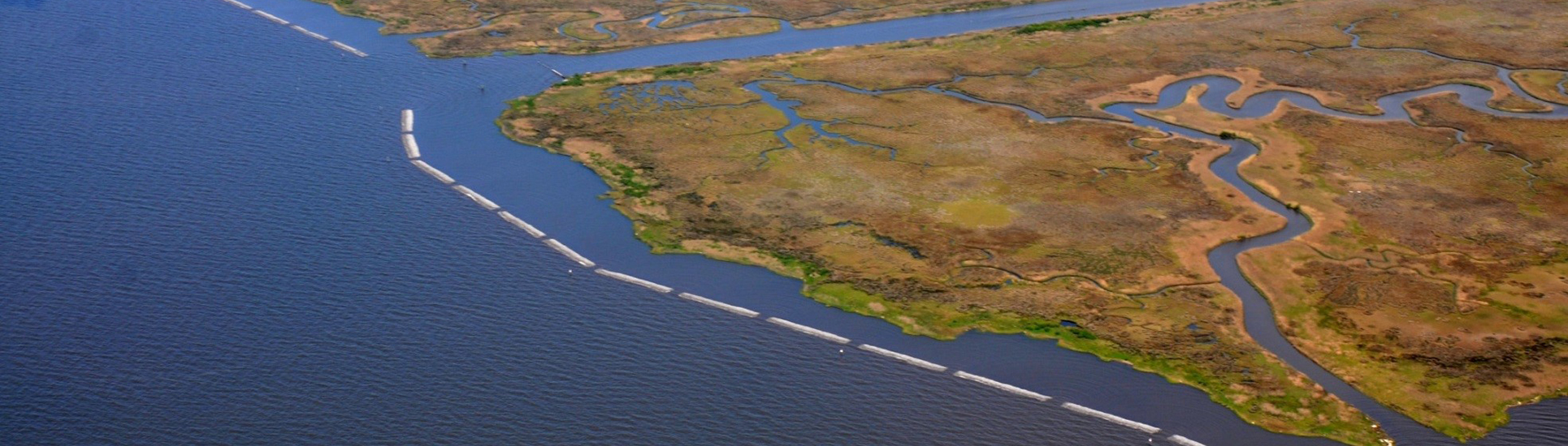 Aerial photo of the Mississippi coast with a living shoreline project that includes natural and artificial breakwater material and marsh creation to reduce shoreline erosion.