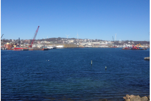 Gloucester Harbor is shown with boats and a crane in the background
