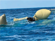 In the clear blue waters off Mona Island Puerto Rico, Divers secure lift bags to the lower portion of a grounded drug running vessel to prepare it for towing back to the main island for proper disposal. 