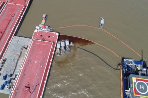 Aerial view of skimmers containing oil on brown water. 