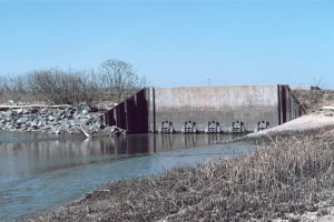 a river is pictured in the foreground of a culvert, with blue sky above 