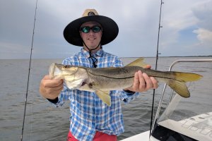 a man in a hat holding a large snook